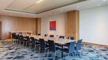 A conference room with a long table, chairs, and a patterned carpet.