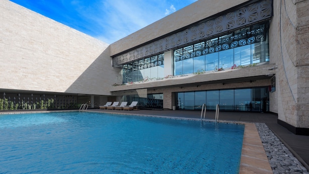 A modern building with a swimming pool, sun loungers, and a glass facade. - Hyatt Place Nairobi Westlands (Nairobi)