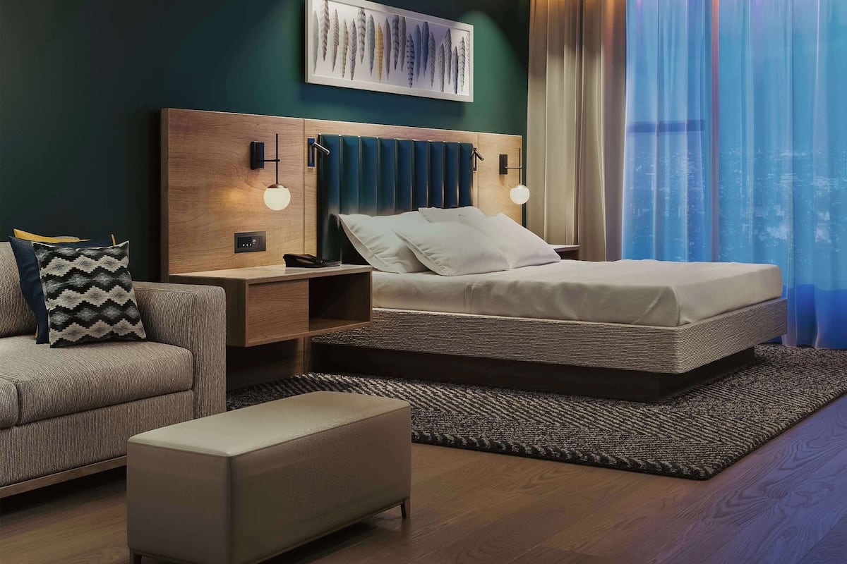 Ein modernes Hotelzimmer mit Bett, Nachttisch, Sofa und Couchtisch.