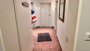 A narrow hallway with a tiled floor, a white door at the end, and a small mat at the entrance. - Ferienwohnung Baalmann Nr. 4 (Borkum)