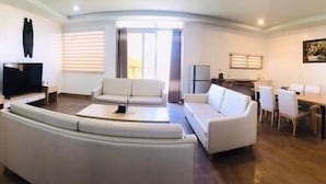 Una sala de estar moderna con un sofá curvo, un televisor de pantalla plana y un comedor con mesa y sillas.