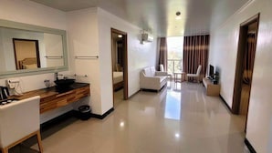 Habitación de hotel con baño, zona de estar y televisor.