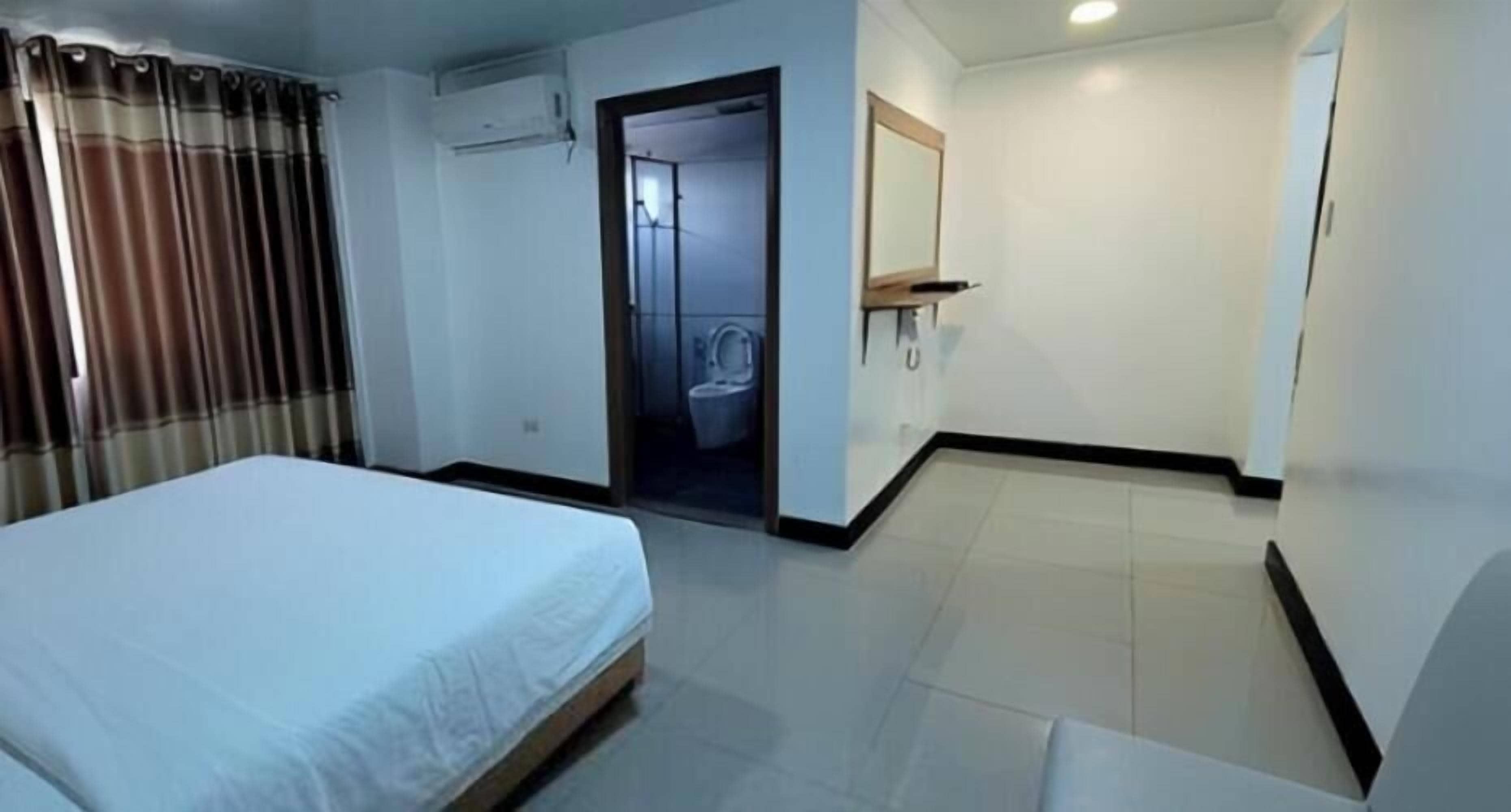 A hotel room with a bed, a bathroom, and a door leading to another room.