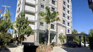 Un hotel de varios pisos con fachada moderna, palmeras en primer plano y un cartel que indica que es el Castle Hotel.