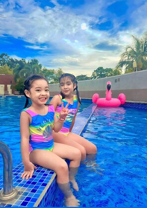 Two children sitting on the edge of a swimming pool with a pink inflatable flamingo in the background. - PUNTA CLARK HOTEL (Mabalacat City)