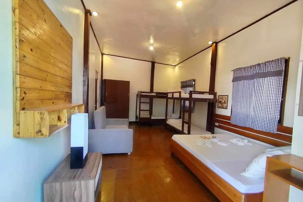 A compact room with bunk beds, a desk, and a small seating area.