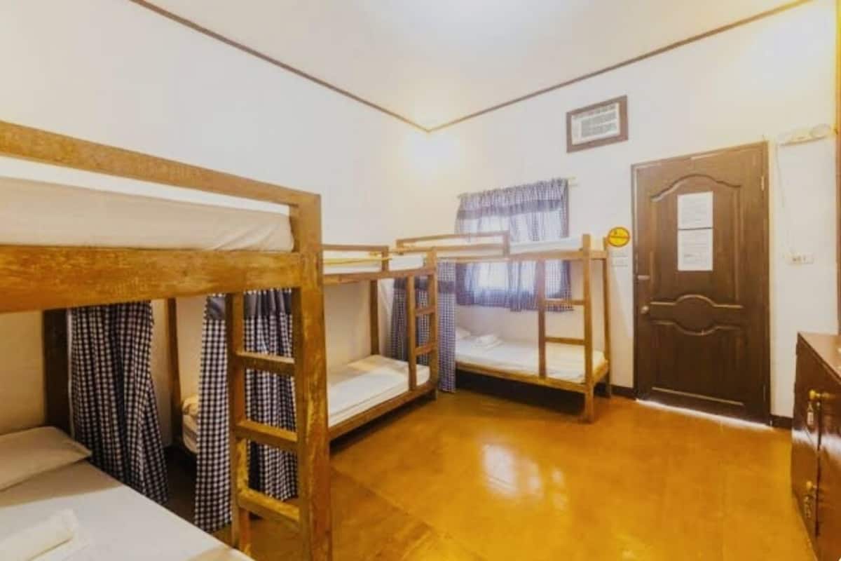 A room with bunk beds, a wooden door, and a window with curtains.