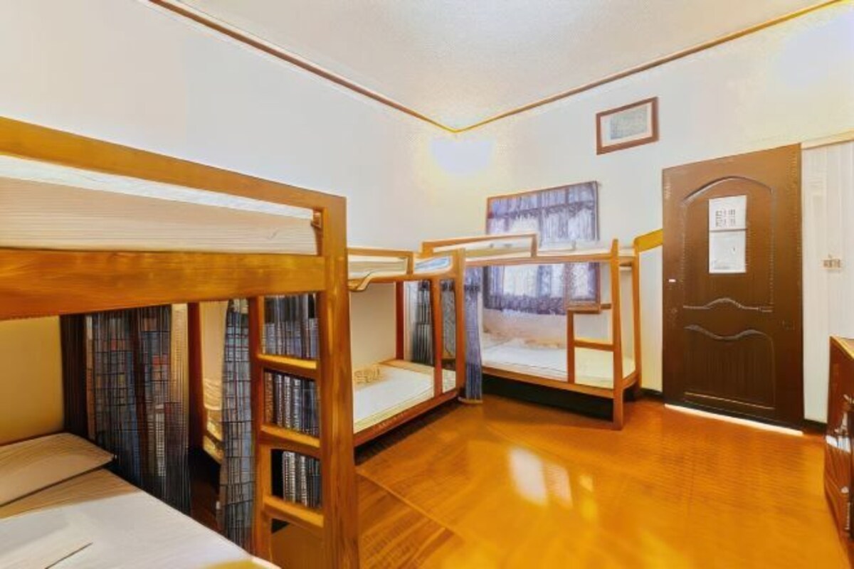 A room with bunk beds, a wooden door, and a small desk.
