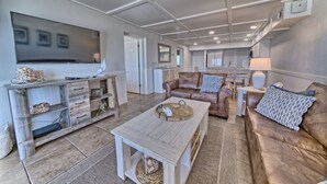 Amplia sala de estar con un televisor grande, muebles de madera y un acogedor conjunto de asientos.