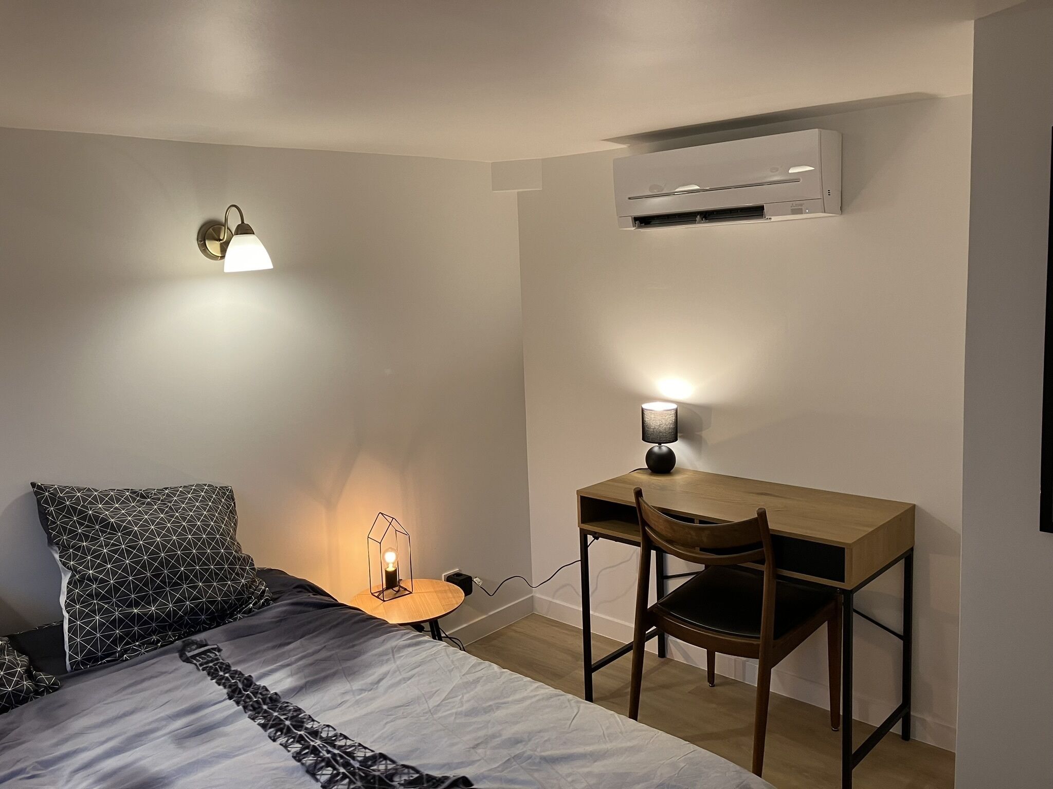 Quarto com cama, escrivaninha e ar condicionado.