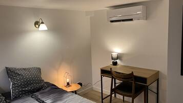 Quarto com cama, escrivaninha e ar condicionado.