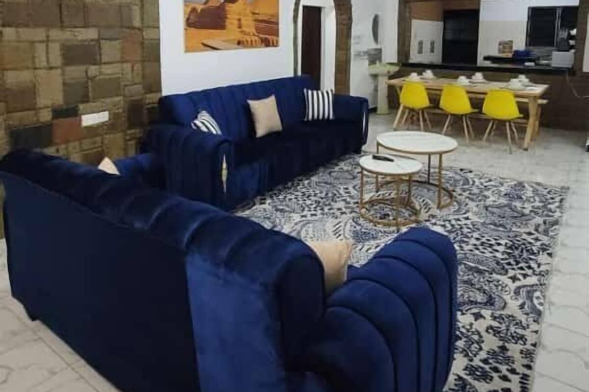 Un saló amb un sofà blau, una catifa amb dibuixos i una paret de pedra.