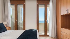 Ein Schlafzimmer mit einem Bett, einem Holzschrank und einer Glastür zum Balkon.