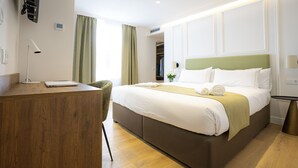 A hotel room with a bed, a desk, a chair, and a small table. - Casa Pince (Barcelona)