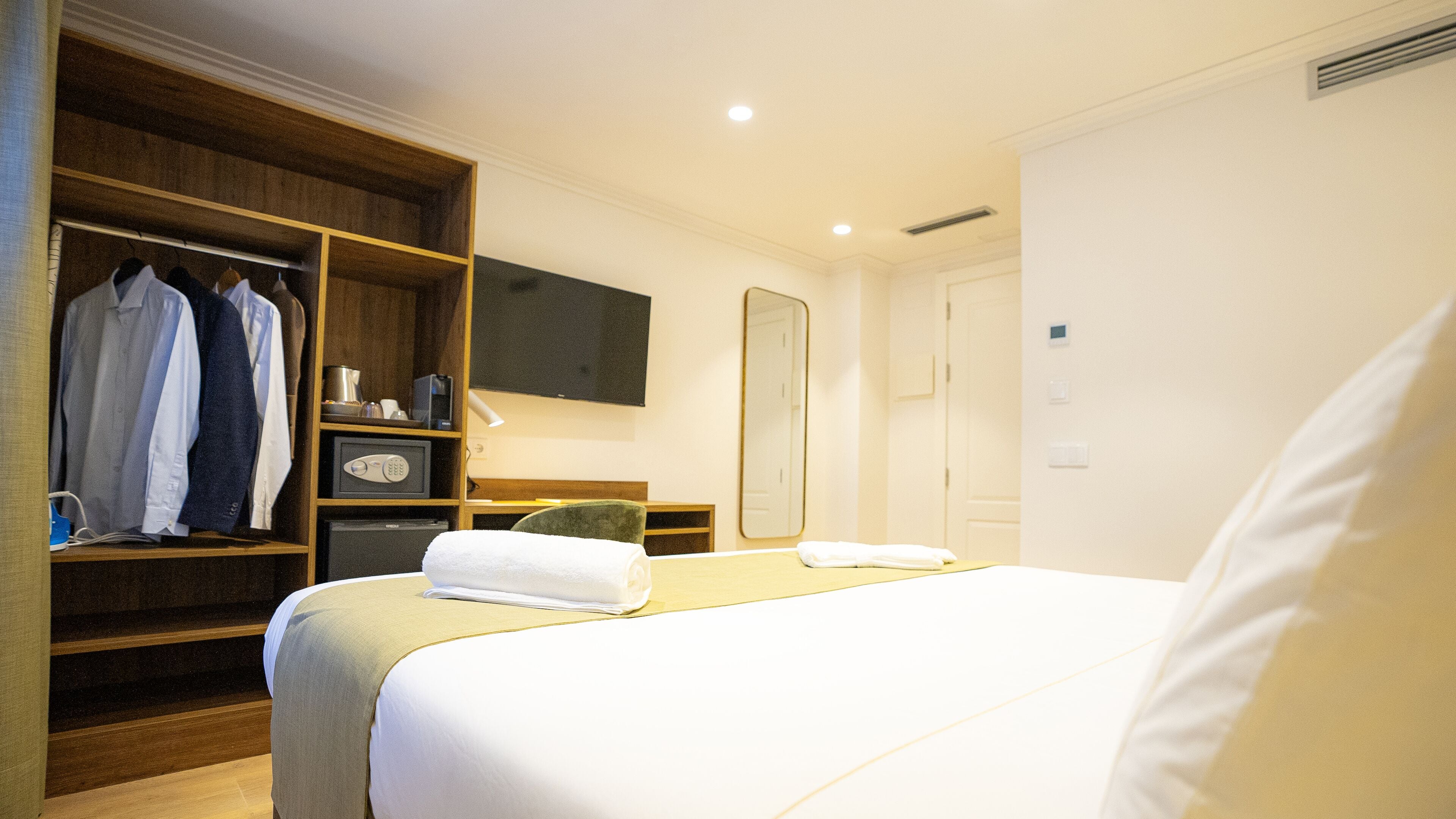 Une chambre d’hôtel comprenant un lit, une armoire, un bureau, un miroir et un téléviseur.