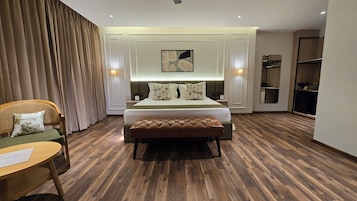Una habitación de hotel con una cama, un banco, una silla, un escritorio y un armario.