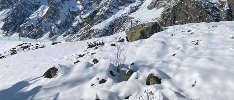 Un paysage montagneux enneigé, avec des affleurements rocheux et un ciel bleu dégagé.