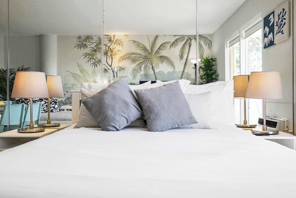 A bedroom with a bed, two bedside tables, and a wall mural. - Vista Mar, Minutes to Beach, Cozy (North Bay Village)