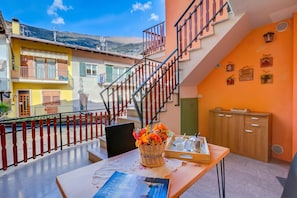 Un balcone con un cesto di vimini pieno di fiori, un tavolo con un libro e una scala.