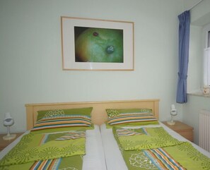 Double bed with two pillows and bedside tables, each with a lamp, in a simple and clean room.