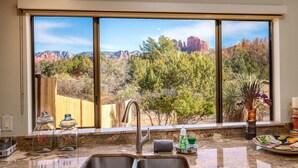 A kitchen with a large window overlooking a mountainous landscape. - Cathedral Views | Large home with two living spaces and kitchens (Sedona)