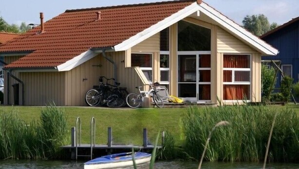 A house with a red roof, a dock, and bicycles parked outside.