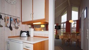 A kitchen with wooden cabinets, a refrigerator, and a coffee maker. There is a dining area with a table and chairs.