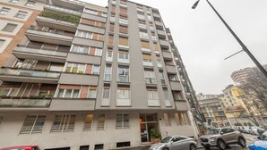 A multi-story residential building with balconies, a visible entrance, and parked cars on the street. - BnButler - Longhena, 7 (Milano)