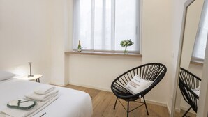 Ein Hotelzimmer mit Bett, Stuhl, Nachttisch, Fenster mit Blick und Spiegel.