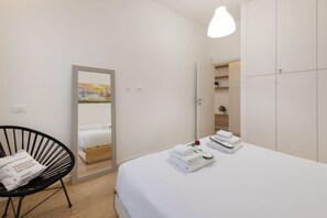 A hotel room with a bed, a chair, a mirror, a wardrobe, and a painting on the wall. - BnButler - Longhena, 7 (Milano)