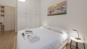 A bedroom with a bed, a bedside table, a lamp, a painting, and a wardrobe. - BnButler - Longhena, 7 (Milano)