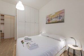 Une chambre à coucher avec un lit, une table de chevet, une lampe, un tableau et une armoire.