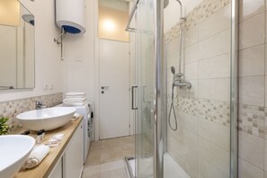 A modern bathroom with a large sink, a glass shower enclosure, and a tiled floor. - BnButler - Longhena, 7 (Milano)