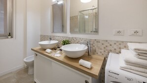 A bathroom with two sinks, a mirror, a towel rack, and a washing machine. - BnButler - Longhena, 7 (Milano)