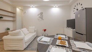 A modern living room with a sofa, dining table, and a TV. - BnButler - Longhena, 7 (Milano)