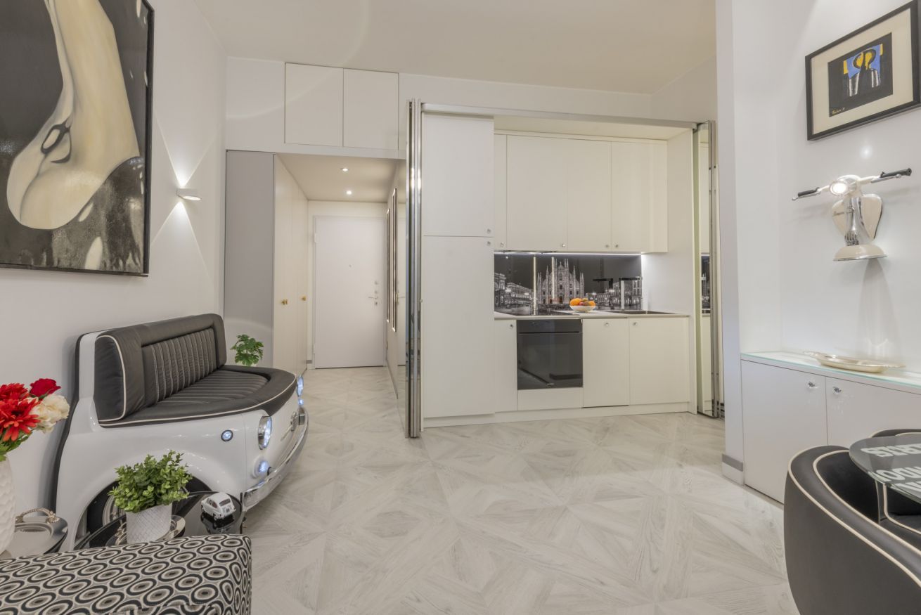 A modern kitchen with white cabinets, a built-in oven, and a stainless steel refrigerator.