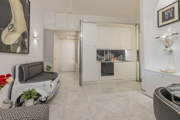 A modern kitchen with white cabinets, a built-in oven, and a stainless steel refrigerator.