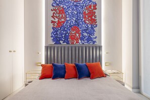 A modern bedroom with a large bed, a decorative wall piece, and a bedside table with a lamp. - BnButler - Falcone, 5 - App. 2 (Milano)