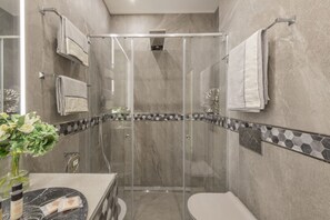 A modern bathroom with a glass-enclosed shower, a toilet, and a vanity with a marble countertop. - BnButler - Falcone, 5 - Apt. 2 (Milano)