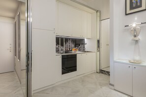 A modern kitchen with white cabinetry, a built-in oven, and a stainless steel range hood. - BnButler - Falcone, 5 - App. 2 (Milano)