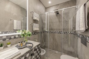 A modern bathroom with a glass-enclosed shower, a marble-tiled wall, and a vanity with a geometric backsplash. - BnButler - Falcone, 5 - App. 2 (Milano)