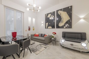 A modern living room with a sofa, a vintage car-shaped coffee table, and abstract wall art.