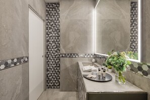A modern bathroom with a large mirror, a sink with toiletries, and a decorative vase. - BnButler - Falcone, 5 - App. 2 (Milano)