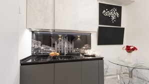 A modern kitchen with a black countertop, a glass table, and a vase with flowers.