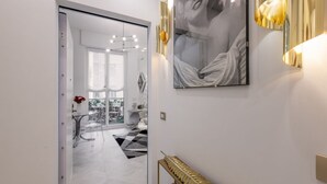 A hallway with a glass door leading to a dining area, a gold decorative console, and a framed artwork on the wall.