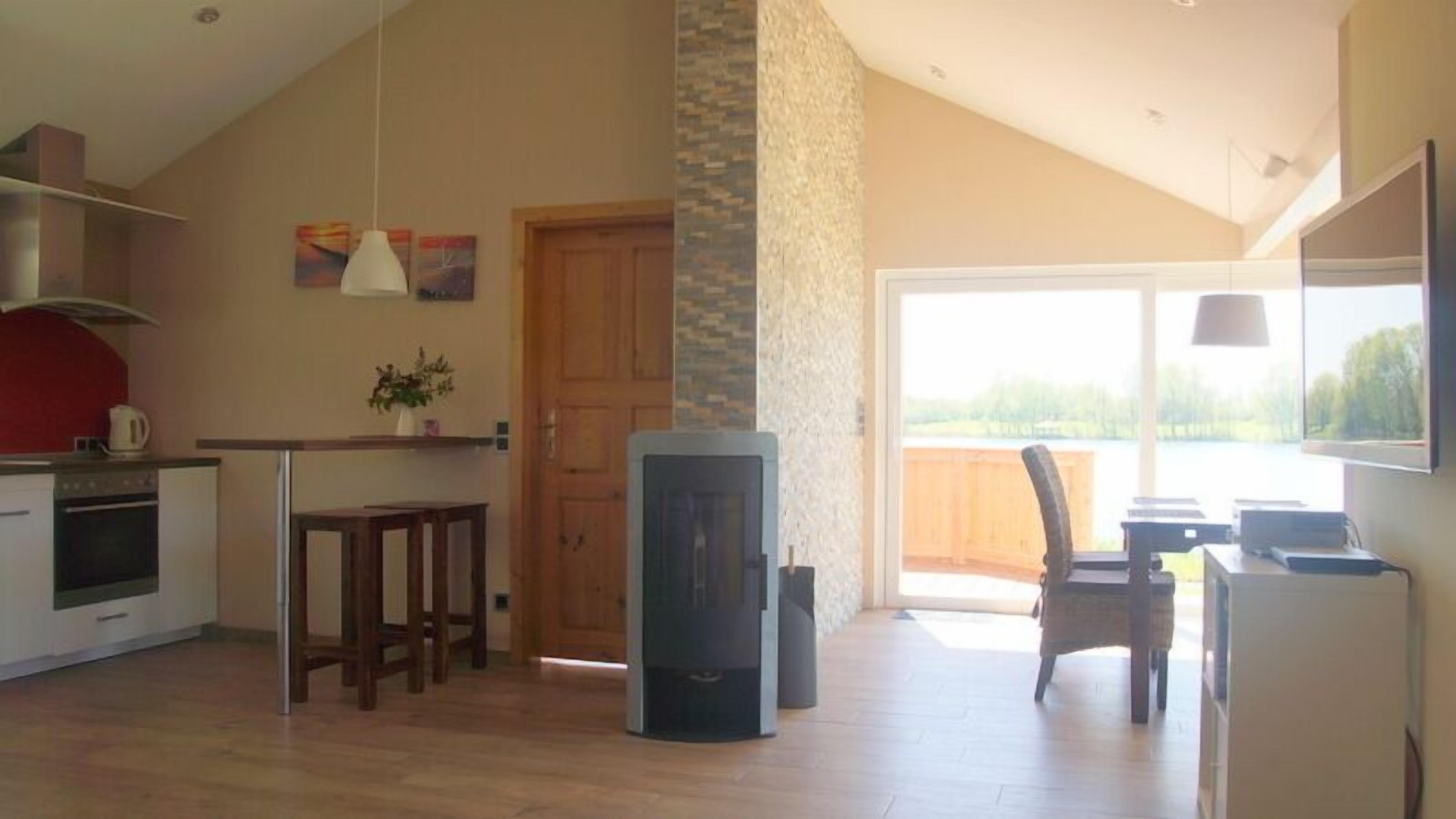 A spacious kitchen with a dining area, a fireplace, and a large window offering a view of the outdoors.