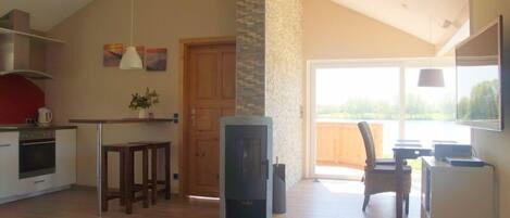 A spacious kitchen with a dining area, a fireplace, and a large window offering a view of the outdoors.