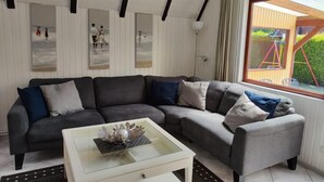 Una sala de estar moderna con un sofá seccional gris, una mesa de centro de vidrio y obras de arte en las paredes.
