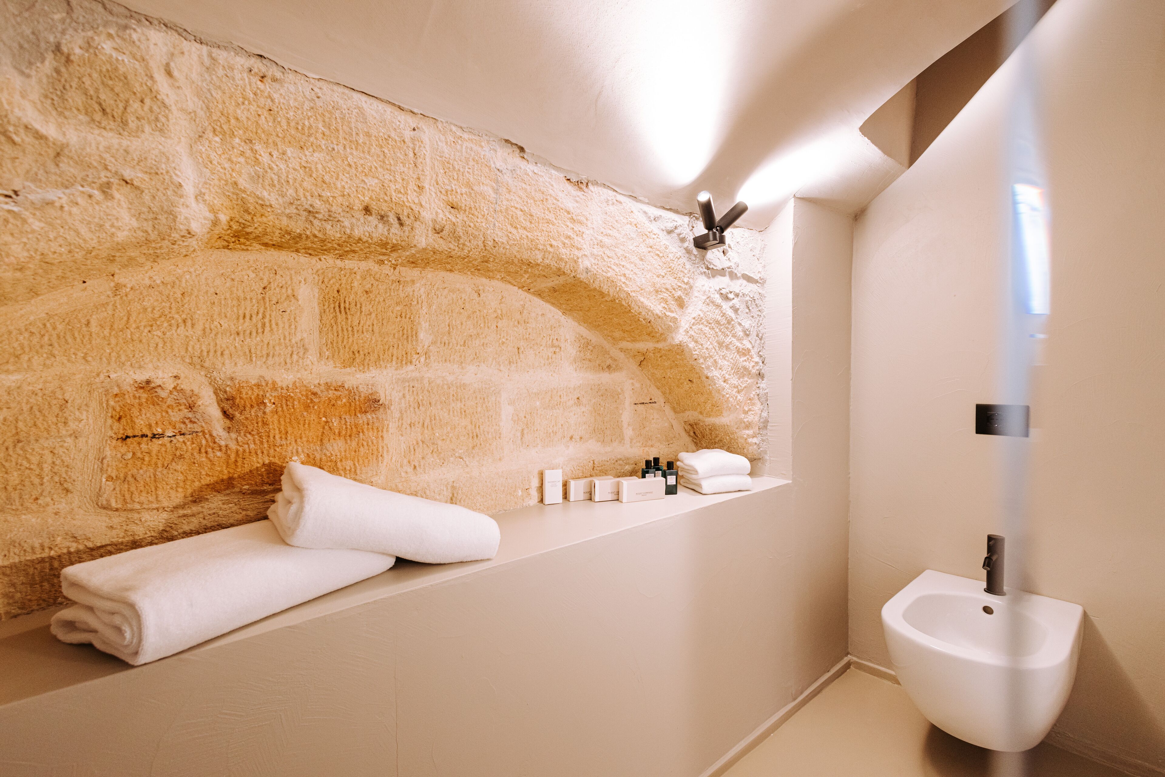 A bathroom with a stone wall, a sink, and neatly folded towels.