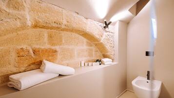 A bathroom with a stone wall, a sink, and neatly folded towels.